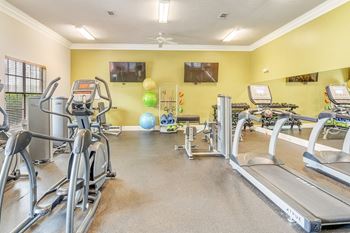 the gym with cardio equipment and weights at villas on the park apartments